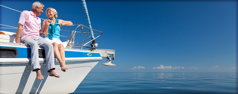 senior couple sits on edge of boat on water