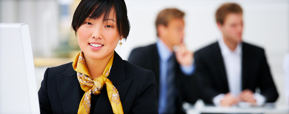 young business woman with yellow scarf smiles with business men in background